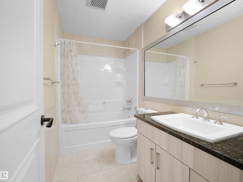 Bathroom featuring a light-toned vanity with dark countertop, integrated sink, and chrome fixtures - 2019 Cameron Ravine Way Nw, Edmonton, AB 