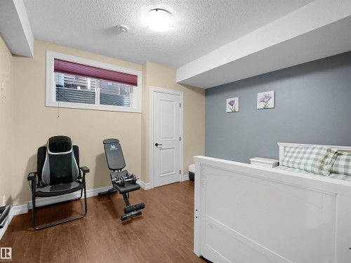 Spacious room featuring wood-finish flooring, a neutral color palette, and a window with a pleated shade - 2019 Cameron Ravine Way Nw, Edmonton, AB 