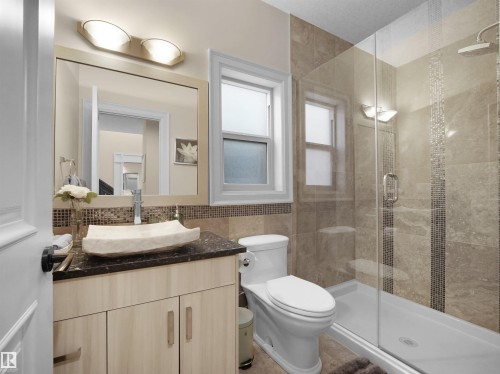 Contemporary bathroom featuring a light wood vanity with a dark countertop and vessel sink - 2019 Cameron Ravine Way Nw, Edmonton, AB 