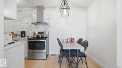 Kitchen area featuring stainless steel appliances, a range with a matching range hood, and a marble-look backsplash - 