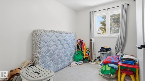 Carpeted interior space featuring light neutral walls and a white-framed window - 20C Callingwood Court, Edmonton, AB - Indoor