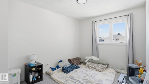 Bright room featuring a window with white trim, light gray walls, and textured ceiling - 20C Callingwood Court, Edmonton, AB - Indoor Photo Showing Bedroom