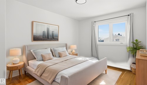 Bright bedroom featuring wood-finish flooring, a large window, white walls, and a contemporary ceiling light fixture - 20C Callingwood Court, Edmonton, AB - Indoor Photo Showing Bedroom