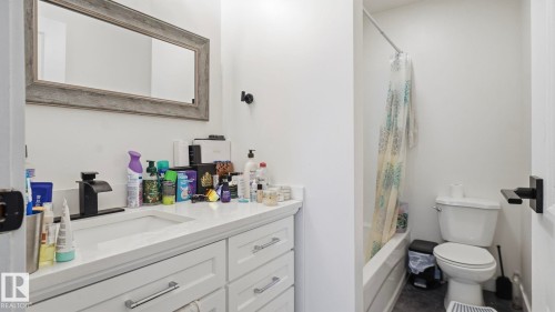 Bathroom featuring a white vanity with an integrated sink, matte black faucet, and a large framed mirror - 20C Callingwood Court, Edmonton, AB - Indoor Photo Showing Bathroom