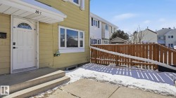 Exterior entry featuring a white paneled door with an arched glass insert, concrete steps, a protective overhang, and vinyl siding - 