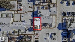 Aerial view highlighting a property with a white roof and surrounding snow-covered terrain - 