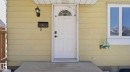 Exterior featuring horizontal siding, a white entry door with an arched window, a wall-mounted light fixture, a black mailbox, and a white-framed window - 20C Callingwood Court, Edmonton, AB  - Outdoor With Exterior 