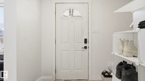 White paneled entry door with an arched glass insert, featuring a contemporary black door handle and smart lock - 20C Callingwood Court, Edmonton, AB - Indoor Photo Showing Other Room