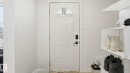 White paneled entry door with an arched glass insert, featuring a contemporary black door handle and smart lock - 20C Callingwood Court, Edmonton, AB  - Indoor Photo Showing Other Room 
