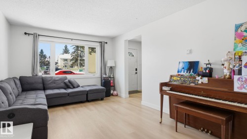 Spacious room featuring wood-finish flooring, white walls, and a large window with white trim - 20C Callingwood Court, Edmonton, AB - Indoor Photo Showing Living Room