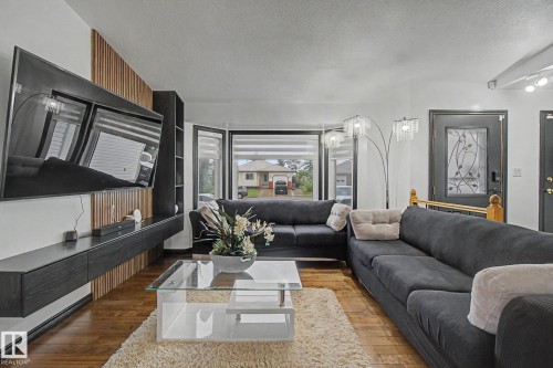 Spacious living area featuring wood-finish flooring and a wood slat accent wall - 242 Northmount Drive, Wetaskiwin, AB 