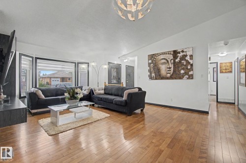 Spacious living area featuring expansive bay windows, wood-finish flooring, and a modern light fixture - 242 Northmount Drive, Wetaskiwin, AB 