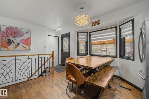 Dining area with wood-finish flooring, a bay window with horizontal blinds, and a decorative crystal chandelier - 242 Northmount Drive, Wetaskiwin, AB 