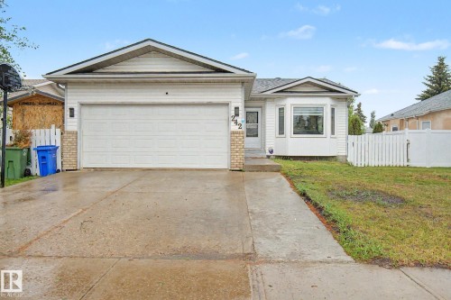 Single-story residence featuring white vinyl siding with brick accents, an attached garage, a bay window, and a concrete driveway - 242 Northmount Drive, Wetaskiwin, AB 