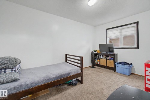 Bedroom featuring white walls, brown carpet flooring, and a single window with blinds - 242 Northmount Drive, Wetaskiwin, AB 