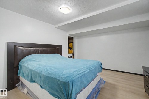 Bedroom featuring light wood-finish flooring, white walls, and a recessed ceiling with exposed beams - 242 Northmount Drive, Wetaskiwin, AB 