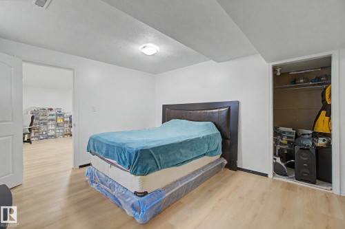Light wood-finish flooring throughout, white painted walls, ceiling-mounted light fixture, open doorway, and a built-in closet with shelving - 242 Northmount Drive, Wetaskiwin, AB 