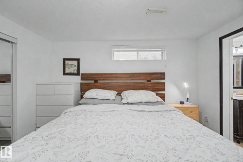 Spacious sleeping area featuring a wood-finish headboard, a window with a white blind, and a white ceiling - 242 Northmount Drive, Wetaskiwin, AB 