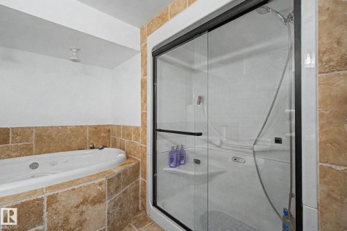 Tiled shower enclosure with sliding glass doors, integrated shelving, and a handheld showerhead - 242 Northmount Drive, Wetaskiwin, AB 