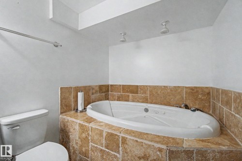 Built-in soaking tub with a tiled surround, recessed ceiling lighting, and a chrome towel bar - 242 Northmount Drive, Wetaskiwin, AB 