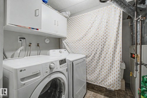 Dedicated laundry area featuring white upper cabinetry, tiled flooring, and exposed utility piping - 242 Northmount Drive, Wetaskiwin, AB 