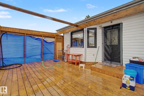 Expansive wood deck with an attached pergola frame, featuring a white siding exterior and multiple windows - 242 Northmount Drive, Wetaskiwin, AB 