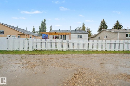 White picket fence enclosing a backyard with a wooden pergola - 242 Northmount Drive, Wetaskiwin, AB 