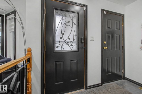 Black paneled entry door with decorative glass inlay and modern hardware - 242 Northmount Drive, Wetaskiwin, AB 