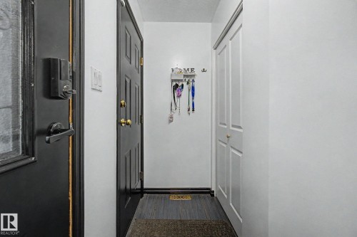 Entryway featuring a dark paneled door, light wood-finish flooring, and a bi-fold closet - 242 Northmount Drive, Wetaskiwin, AB 