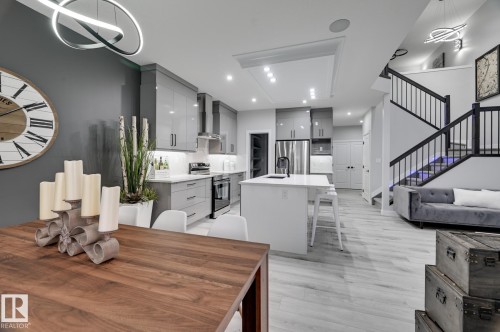 Open-concept living area featuring a modern kitchen with high-gloss cabinetry, a central island with integrated seating, and stainless steel appliances - 54 Chartres Close, St. Albert, AB - Indoor