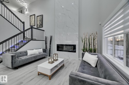 Double-height living space featuring wood-finish flooring and a full-height fireplace with a linear insert - 54 Chartres Close, St. Albert, AB - Indoor Photo Showing Living Room With Fireplace