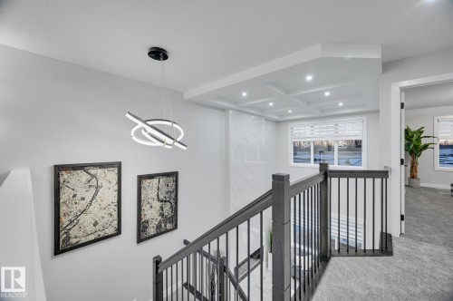 Upper-level landing featuring a contemporary chandelier, recessed lighting, coffered ceiling detail, and a window with blinds - 54 Chartres Close, St. Albert, AB - Indoor Photo Showing Other Room