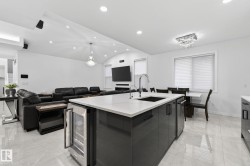 Open-concept living space featuring a kitchen island with a built-in beverage cooler, white countertop, and integrated sink - 