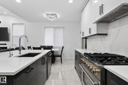 Modern kitchen featuring white countertops, light tile flooring, and integrated stainless steel appliances - 