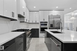 Modern kitchen featuring white glossy upper cabinetry, dark lower cabinetry, and light-toned countertops - 