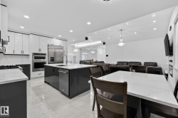 Modern kitchen featuring glossy white upper cabinetry, dark lower cabinetry, and light countertop surfaces - 