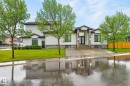 Contemporary exterior featuring white siding and stone accents, a prominent entryway with double doors, dark-framed windows, a concrete driveway, and a manicured lawn - 7304 164 Avenue, Edmonton, AB  - Outdoor With Facade 