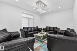 Brightly lit interior space featuring a large window with white blinds, recessed ceiling lighting, and a prominent crystal chandelier - 