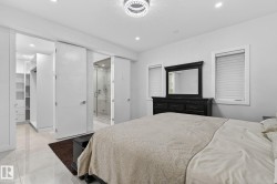 Spacious bedroom featuring light-toned flooring, recessed lighting, and a modern chandelier - 