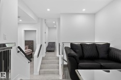Modern interior featuring recessed lighting, a glass and metal railing, a staircase with tile flooring, and a white color palette - 