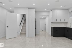Contemporary kitchen space featuring two-tone cabinetry, a stainless steel sink, and a marble-finish backsplash - 