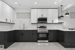 Contemporary kitchen featuring two-tone cabinetry, quartz countertops, a matching backsplash, and stainless steel appliances - 