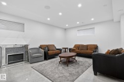 Spacious living area featuring light tile flooring, recessed lighting, and a decorative fireplace with a mirrored surround - 