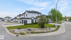 Contemporary two-story residence featuring a light-colored stucco exterior, dark shingle roof, attached garage, and multiple large windows - 