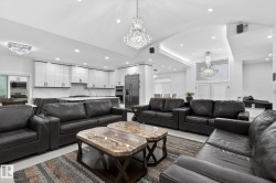 Spacious open-concept living area featuring a vaulted ceiling and elegant crystal chandeliers - 