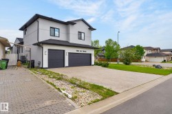 Modern two-story residence featuring a light-colored stucco exterior with dark trim and a black shingle roof - 