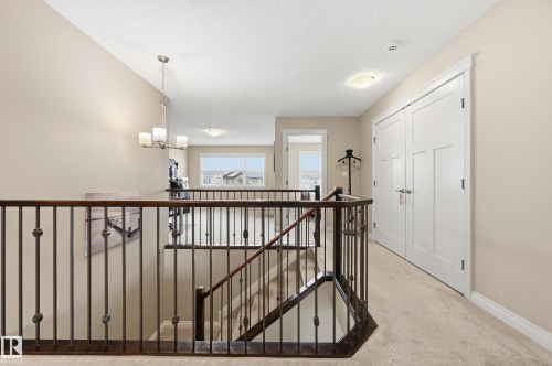 Upper-level hallway featuring a dark wood handrail with decorative metal balusters - 1111 176 Street, Edmonton, AB 