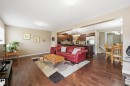 Open-concept living space featuring wood-finish flooring, recessed lighting, and a large window with blinds - 1111 176 Street, Edmonton, AB 