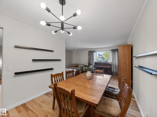 Dining area featuring a contemporary sputnik chandelier, light wood-finish flooring, and white baseboards - 18416 90 Avenue, Edmonton, AB 