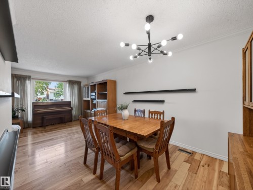 Dining area featuring wood-finish flooring, a contemporary black sputnik chandelier, and white wall finishes - 18416 90 Avenue, Edmonton, AB 